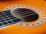 Puinen akustinen kitara, jonka kaikukopan päällä kieliä siistissä rivissä tasaisin välein. Kaikukopan suuaukkoa ympäröi koristeellinen kuvio.