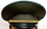 Sotilashattu, jossa musta kiiltäväpintainen lippa ja sen yllä keltaiset kroistenauhat. Hatun väri on armeijanharmaa ja sen lierissä kulkee ohut sininen kanttinauha.