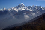 Valokuva Intian puoleisesta Himalajasta. Vuoriston huiput ovat valkoisen lumen peittämiä. Vuorten taustalla sininen pilvetön taivas, mutta vuorenrinteellä vaaleaa sumua tai utua.