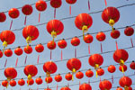 Kiinalaisia lyhtyjä monessa rivissä sinertävää taivasta vasten. Lyhdyt ovat punaisia ja ne ovat pallonmuotoisia.