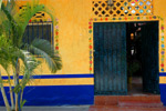 Värikäs kellertävä ja sinertävä seinä, jossa oleva ovi on maalattu tummansiniseksi. Seinän alaosa on siniseksi kalkittu.