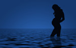 Sinisävyinen valokuva tai maalaus tai piirros raskaana olevan naisen siluetista. Nainen seisoo polviaan myöten laineilevassa meressä katsellen suurta raskausmahaansa.